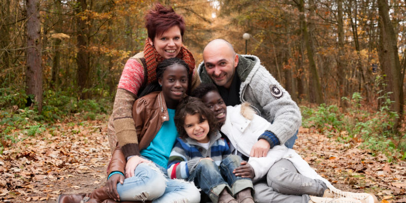 Happy family with foster children in the forest